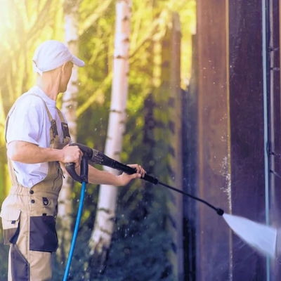 A man pressure washing a fence